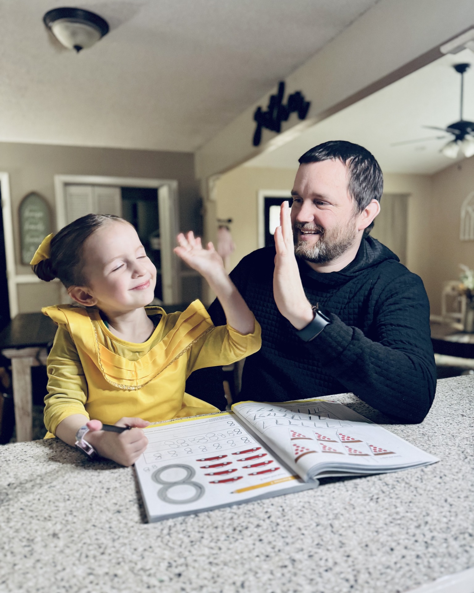 Jerrod Ball high-fiving his daughter over her math workbook